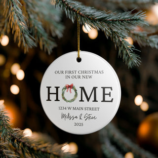 Custom new home ornament hanging on Christmas tree, featuring personalized address and festive wreath for couples.