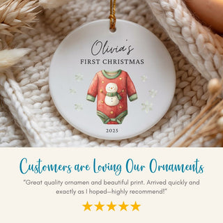 Personalized Christmas ornament with a baby onesie design and text on a textured surface.