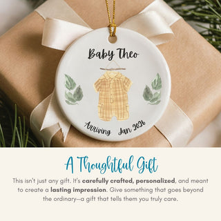 Personalized ornament with baby clothes design on a wrapped gift, featuring text 'Baby Theo Arriving Jan 2023'.